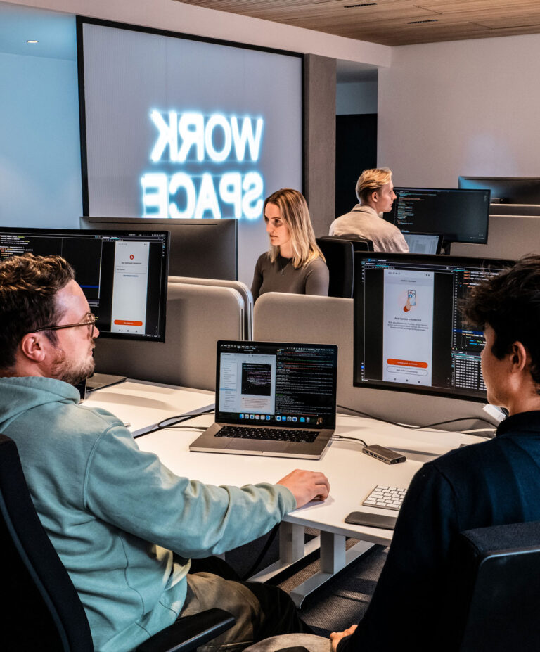 Softwareentwickler:innen der Star Finanz arbeiten im modernen Workspace mit mehreren Monitoren an der Programmierung und Gestaltung digitaler Anwendungen.