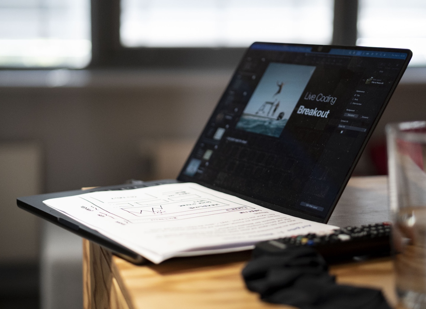Geöffneter Laptop mit einer Präsentationsfolie ‚Live Coding Breakout‘ auf dem Bildschirm, daneben liegen Notizen auf einem Tisch.