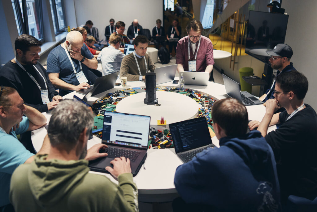 Eine Gruppe von Entwickler:innen arbeitet an ihren Laptops an einem runden Tisch beim DevFest Hamburg 2025.