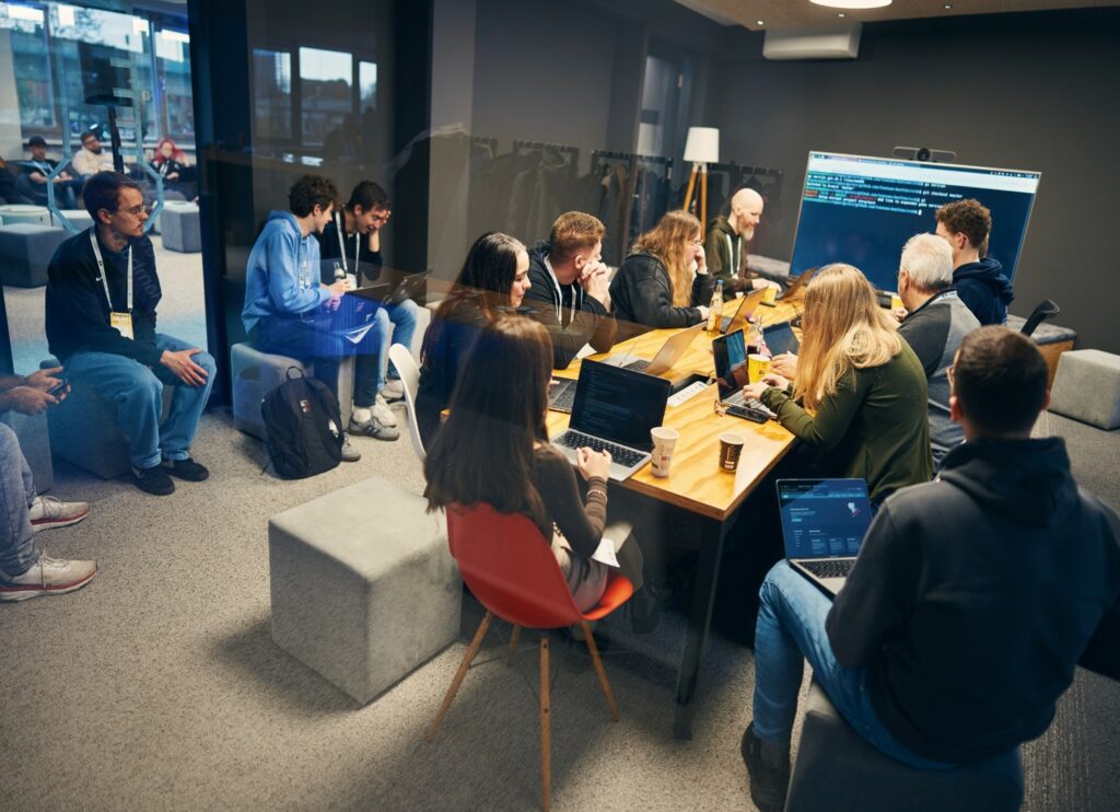 Entwickler:innen in einem Workshop, im Hintergrund ist ein Code auf einem Display zu sehen