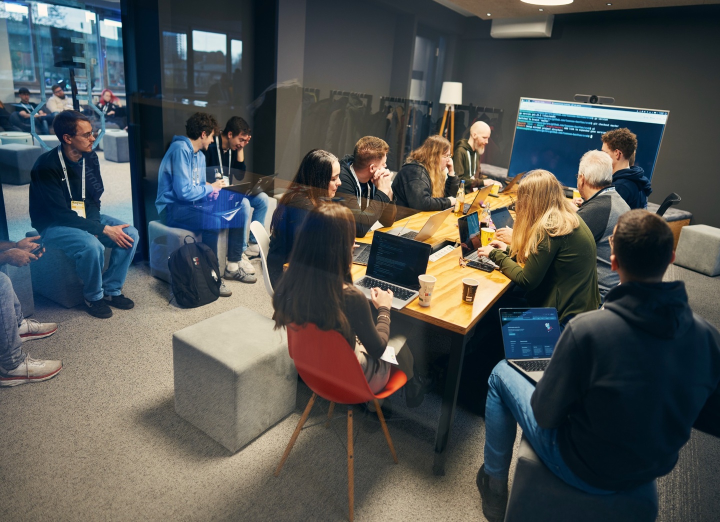 Entwickler:innen in einem Workshop, im Hintergrund ist ein Code auf einem Display zu sehen