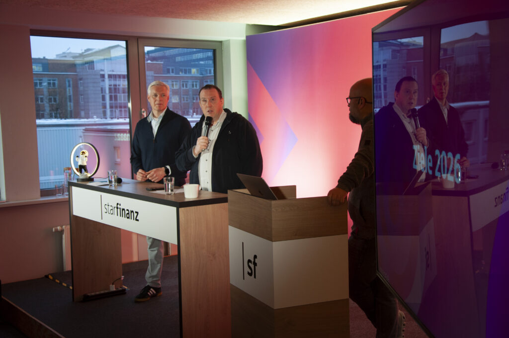 Jochen Balas, Martin Tobies und Jens Rieken, Geschäftsführer der Star Finanz, auf der Bühne beim unternehmensweiten Jahreskickoff 2026.