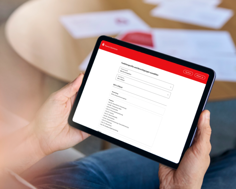 Mitarbeiter hält ein Tablet mit einem Screen des KI-gestützten Rollen- und Rechte-Managements der Taunus Sparkasse in den Händen