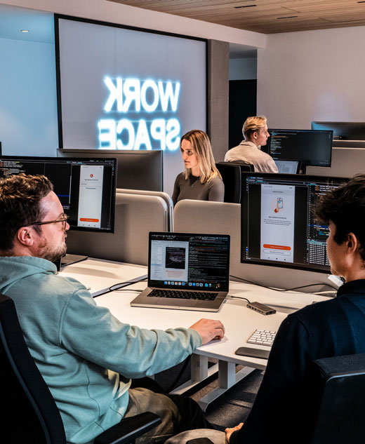 Duale Student:innen und Auszubildende sitzen zusammen und entwickeln Software.