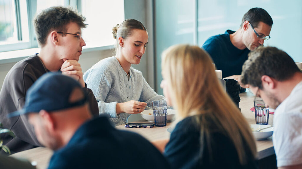Mitarbeitende der App Factory essen gemeinsam und unterhalten sich dabei