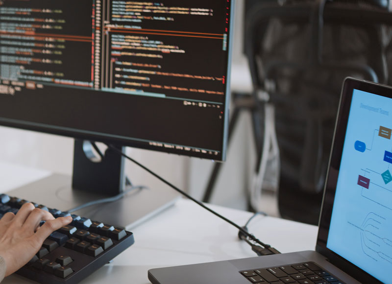 Entwicklerin programmiert Code, verschiedene Bildschirme sind zu sehen.
