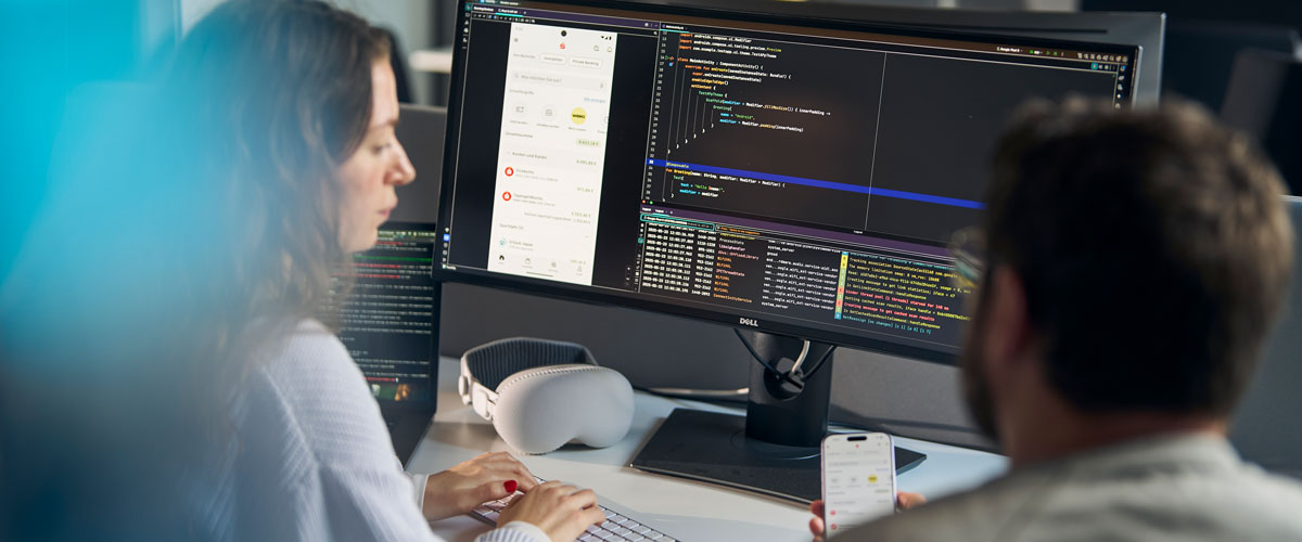 Mann und Frau sitzen ihren Rechnern und programmieren gemeinsam an der Sparkassen App.