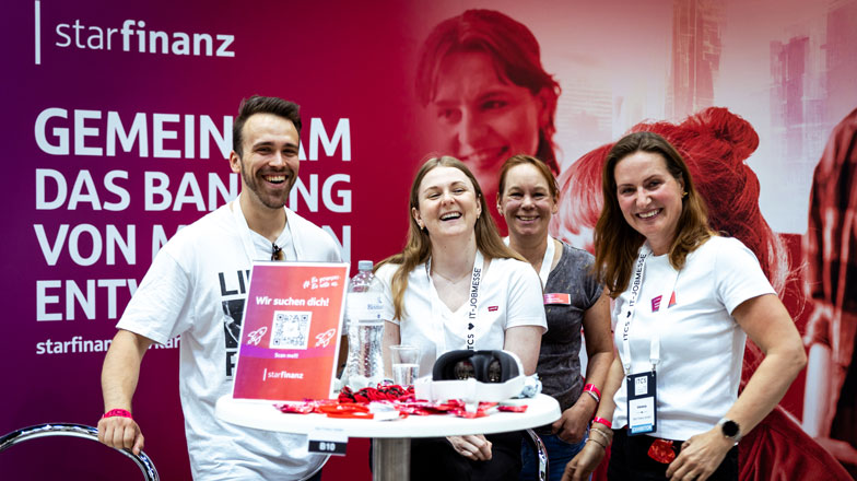 Ein Mitarbeiter und drei Mitarbeiterinnen der Star Finanz stehend fröhlich lachend vor dem Messestand bei der Personalmesse ITCS.