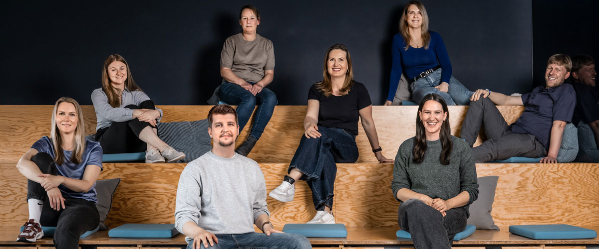 Ein Team von 8 Personen des Bereichs People, Culture and Places der Star Finanz, bestehend aus Männern und Frauen sitzt auf einer Tribüne.