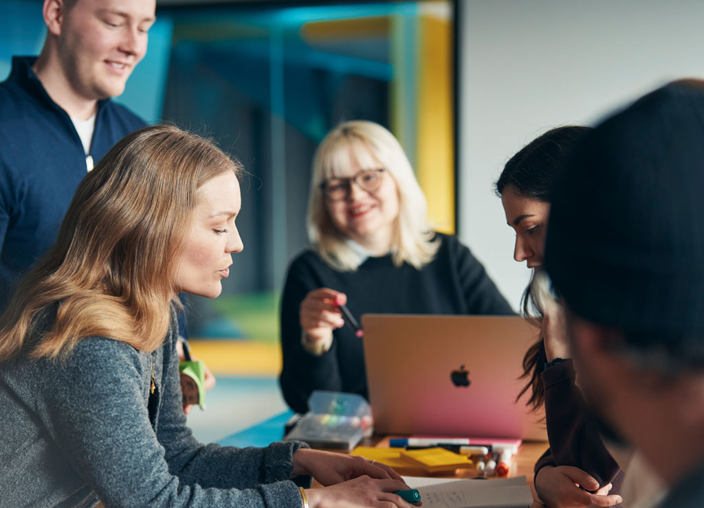 Ein Team von 5 Personen arbeitet im Rahmen eines Workshops gemeinsam an einem Projekt.