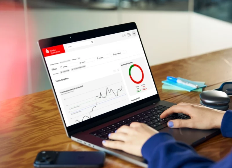 Eine Person, von der nur die Hände zu sehen sind, sitzt vor einem aufgeklappten Laptop, auf dem eine Bankingsoftware der Sparkasse zu sehen ist.