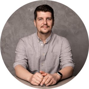 Portrait von Markus Meier von der Star Finanz, der lächelnd am Tisch sitzt, vor grauem Hintergrund.