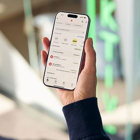 Eine Person schaut auf ihr iPhone auf dem die App Sparkasse geöffnet ist.