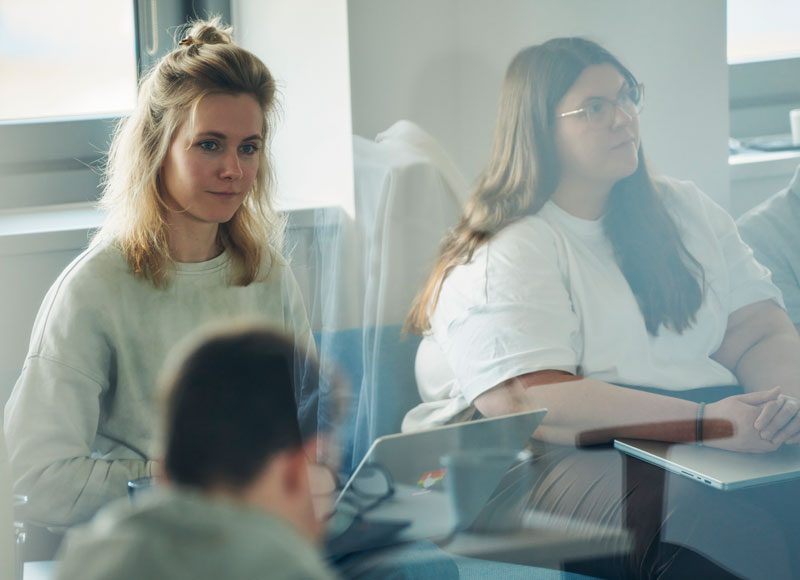 Zwei Frau sitzen nebeneinander in einem Workshop und hören dem Vortrag zu.