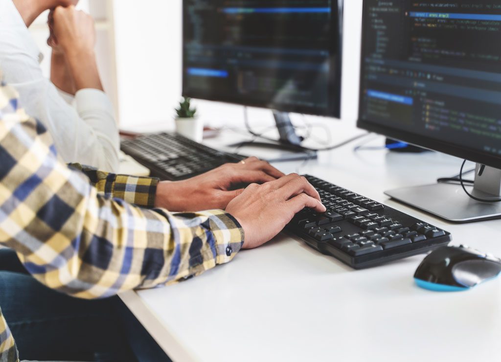 Zwei Entwickler sitzen vor ihren Bildschirmen und schreiben Code.