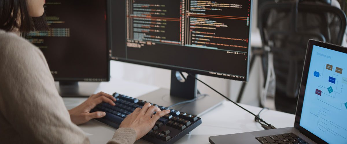 Entwicklerin programmiert Code, verschiedene Bildschirme sind zu sehen.