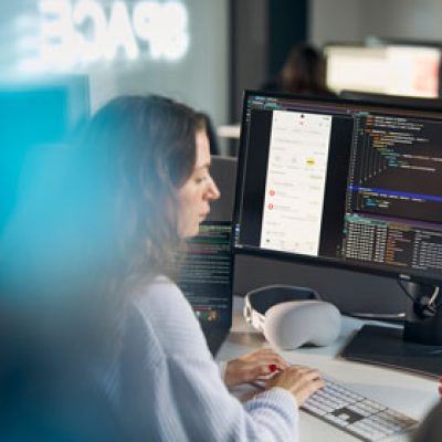 Eine Frau sitzt vor ihrem Rechner und programmiert an der App Sparkasse.