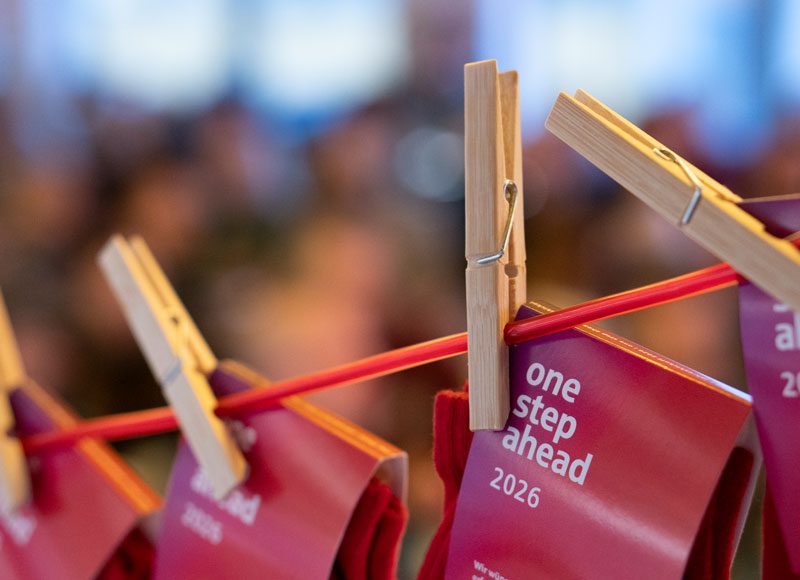 An einer Wäscheleine hängen Socken auf denen "One step ahead 2026" steht.