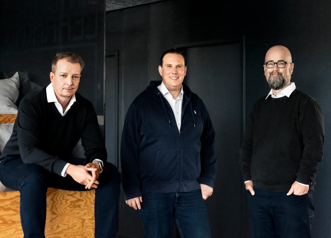Maik Ludewig, Jochen Balas und Jens Rieken, Geschäftsführung der Star Finanz, stehen gemeinsam in entspannter Pose vor dunklem Hintergrund.