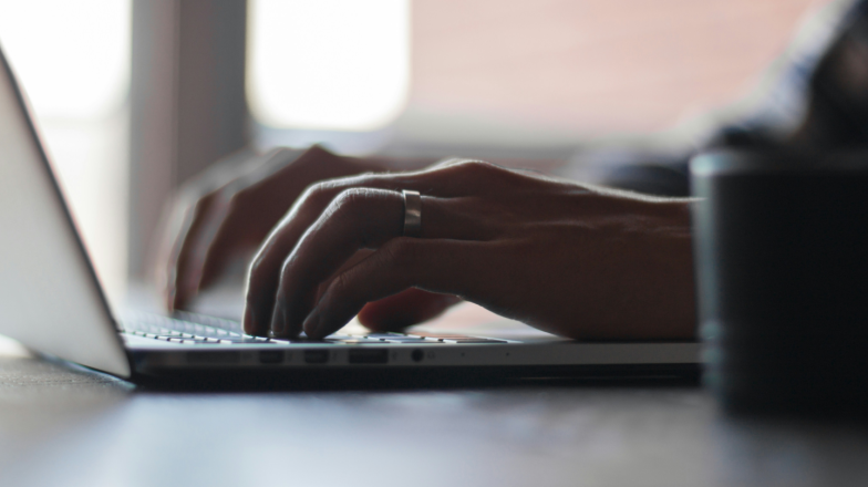 Nahaufnahme von Händen, die auf der Tastatur eines Laptops tippen, mit Fokus auf die Fingerbewegung – im Kontext Verification of Payee.