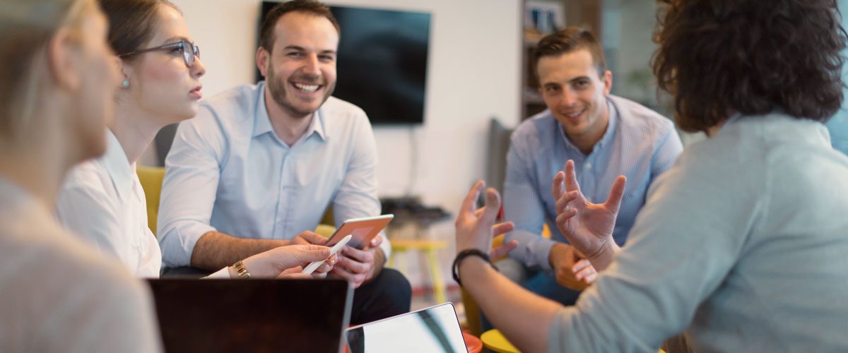 Vier Kolleg:innen sitzen in einem Meeting zusammen und btauschen sich aus.